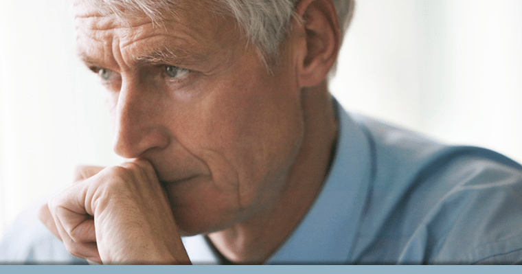 Older man thinking about options for missing teeth with hand against his mouth.