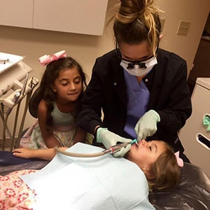 One of Dr. Sarant's hygienist giving a cleaning to a child patient, demonstrating family dentistry in Raleigh, NC