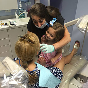 One of Dr. Sarant's hygienist giving a teaching a child patient the importance of family dentistry in Raleigh, NC