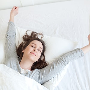 Well-rested woman getting out of bed after a good night's sleep.